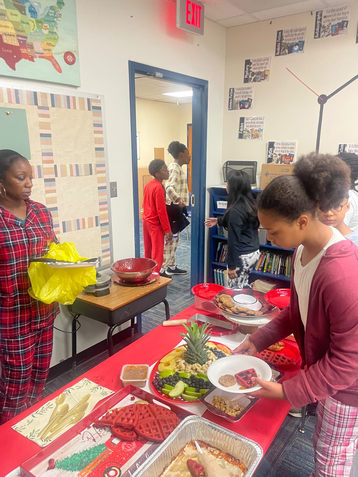 Students serving themselves fresh fruit and waffles at a classroom breakfast