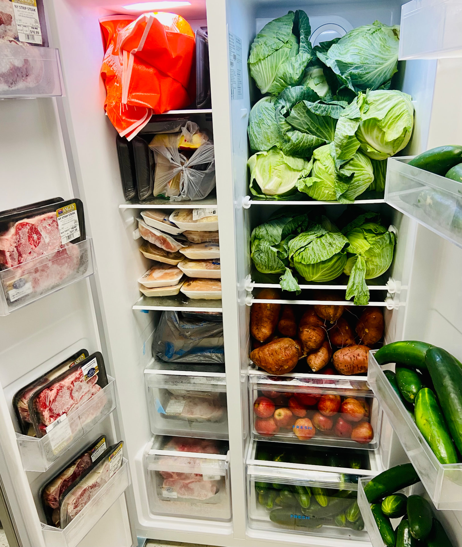 A community fridge stocked with fresh cabbage, sweet potatoes, and produce